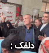 a group of people are standing in a room with their hands in the air and a man is standing in the middle of the room .