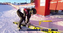 leo lemare is skiing down a slope with a scoreboard behind him