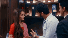 a man and a woman are standing next to each other in a bar talking to each other .