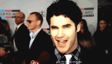 a man is smiling in front of a wall that says american music awards on it