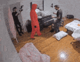 a man in a red hooded jumpsuit is standing in a bedroom with a number 4 on the wall behind him