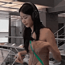 a woman wearing headphones is standing in front of a staircase in a room .