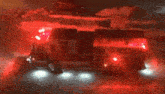 a fire truck is driving down a road at night with red lights on .