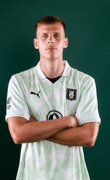 a man wearing a green and white shirt with a puma logo on the sleeve