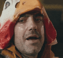 a man with a chicken mask on his head looks at the camera