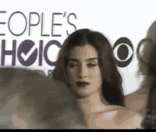 a woman is standing on a red carpet in front of a sign that says people 's choice .