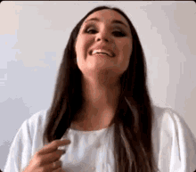 a woman with long dark hair is smiling and holding her hair in her hand .