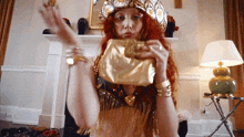 a woman with red hair is holding a gold purse in her hand