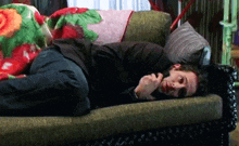 a man is laying on a couch with a floral blanket on it