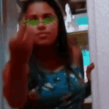 a woman wearing green sunglasses is taking a picture of herself in the mirror .