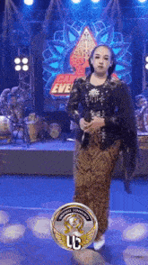 a woman is standing on a stage holding a microphone in front of a can eve sign .