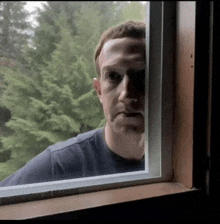 a man is looking out of a window and making a face .