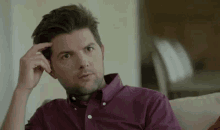 a man is sitting on a couch with his hand on his head .
