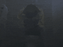 a person in a yellow jacket is sitting on a toilet in the dark