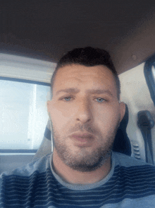 a man with a beard is wearing ear buds in a car