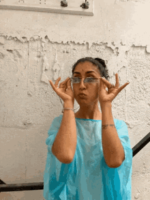 a woman wearing a blue shirt and glasses looks at the camera