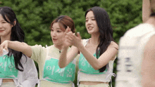 a group of young women are standing next to each other wearing green vests with chinese writing on them .