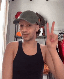 a man wearing a hat and glasses is giving the peace sign