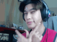 a man wearing headphones and a pink shirt making a face