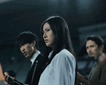 a woman in a white shirt looks down while a man in a suit looks at his phone