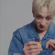 a man in a blue denim jacket is holding a lighter