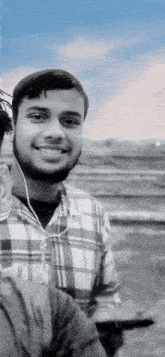 a black and white photo of a man wearing ear buds and a plaid shirt