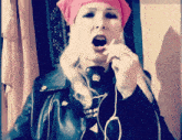 a woman wearing headphones and a pink headband looks at the camera with her mouth open