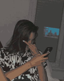 a woman sitting on a couch looking at her cell phone
