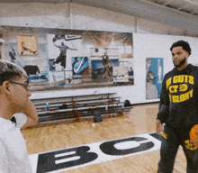 a man wearing a hoodie that says no guts glory talks to another man