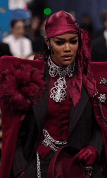 a woman wearing a red head scarf and a black and red suit