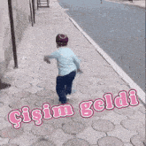a little boy is running down a sidewalk with the words gisim geldi written on the sidewalk