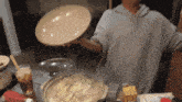a person is holding a plate over a bowl of food