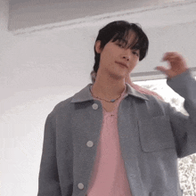 a young man is wearing a pink shirt and a grey jacket .
