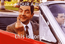 mr bean is giving the middle finger while driving a red car .