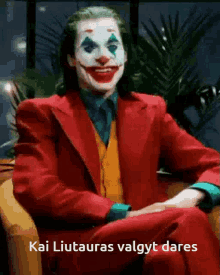 a man in a joker costume is sitting on a couch and smiling .
