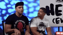 two men sitting in front of a sign that says ae wrestling