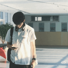 a man in a white shirt is looking at his phone in a room