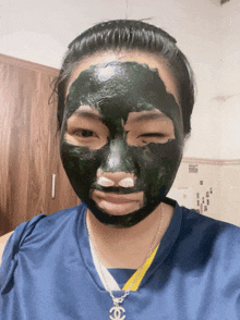 a woman wearing a chanel necklace has a black face mask on her face