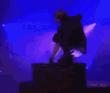 a silhouette of a person sitting on a box in front of a blue light