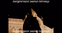 a man is standing in front of a building with russian writing on the bottom right