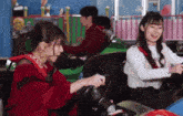 two girls are riding a bumper car in an amusement park .