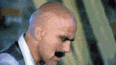 a bald man with a mustache is wearing a white shirt