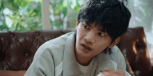 a young man is sitting on a couch looking at something .