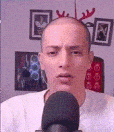 a man wearing a reindeer headband looks at the camera in front of a microphone