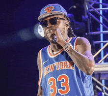 a man singing into a microphone wearing a blue new york jersey