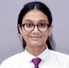 the girl is wearing glasses and a tie and smiling .