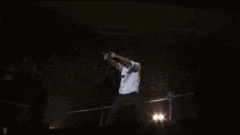 a man in a white shirt is singing into a microphone and giving a thumbs up