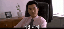 a man in a pink shirt and tie sits in an office chair