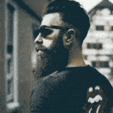 a man with a beard is wearing sunglasses and a black shirt with rolling stones on the back