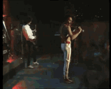 a man playing a guitar on a stage with the word queen on the back